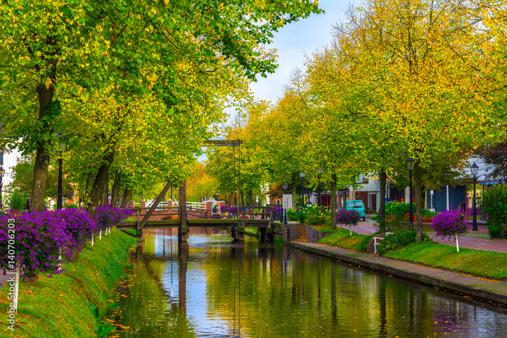Papenburg. Colorful city view with canal and street seamed by trees