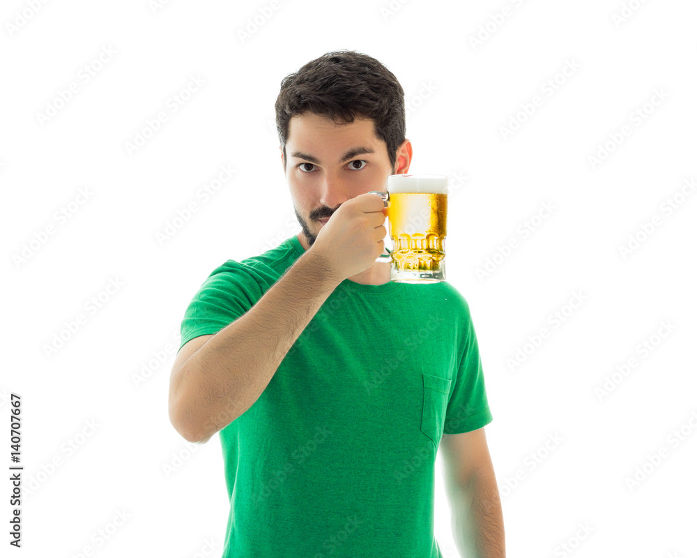Handsome man shows a mug with bier. Wearing green clothes Handsome man shows a mug with bier. Wearing green clothes
