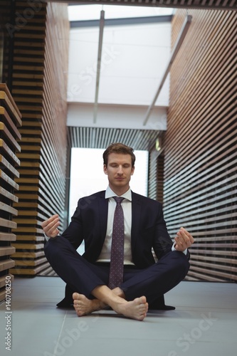 Businessman performing yoga in the corridor