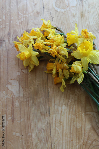 Fototapeta Naklejka Na Ścianę i Meble -  Wilted daffodil flowers on a wooden table
