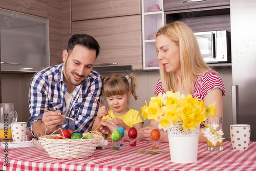 Happy Mother and Father with Kid Decorating Easter Eggs On Kitchen Table 