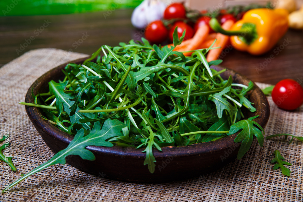 Arugula leaves in bowl. Fresh salad. Pepper and cherry tomatoes. Natural raw vegetables. Organic bio food on rustic wooden table. Arugula leaves in bowl. Fresh salad. Pepper and cherry tomatoes. Natural raw vegetables. Organic bio food on rustic wooden table.