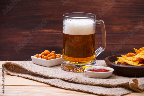 Glass of beer. Nachos chips. Tortilla snack. Mexican salsa nuts. Appetizer with sweet salsa or chilli sauce. Mug or pint of ale. On rustic wooden background.