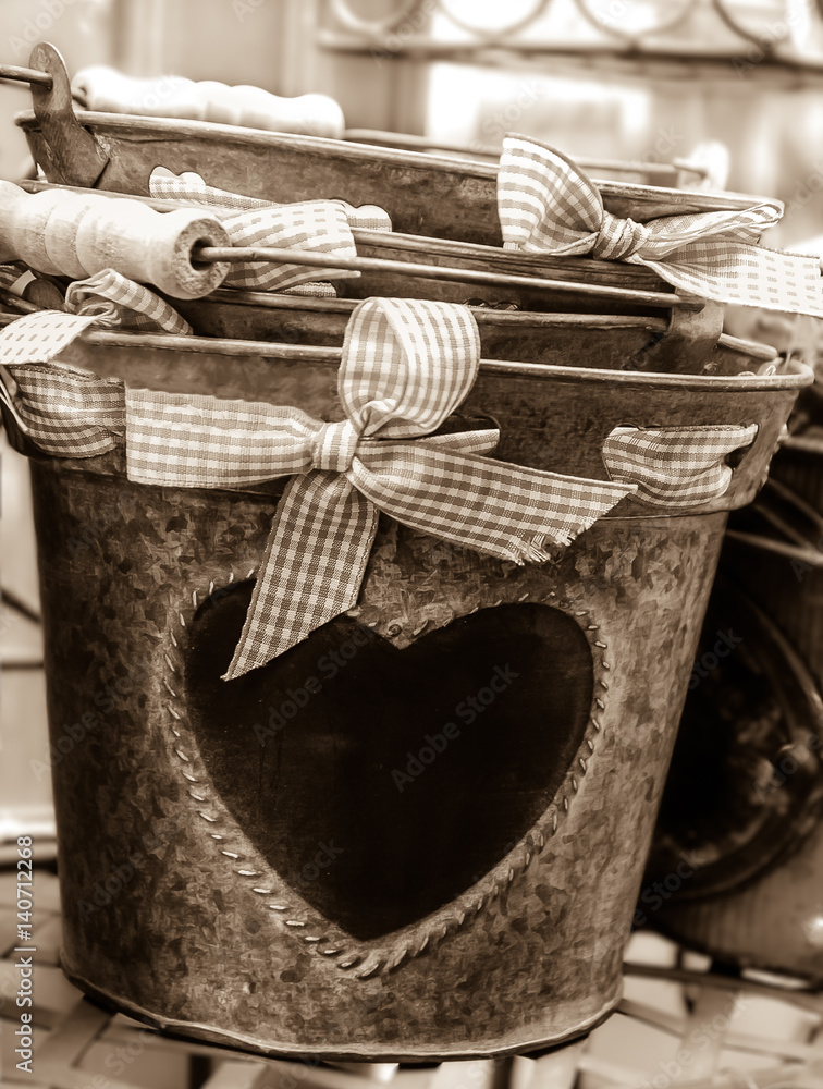 Cultivate your Love! Valentines day background. Buckets decorated with heart shape and red checked bow.  Sepia.