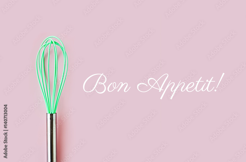 Neon green culinary whisk top view on colorful background. Bon Appetit text. Cook food concept  