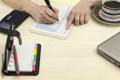Una persona escribe en un bloc de facturas, sobre una mesa de oficina photo