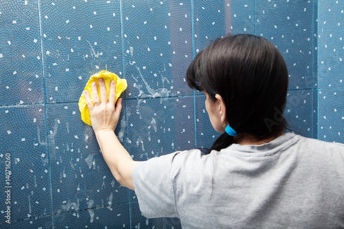 Close-Up rear view of a woman cleaning bathroom tiles