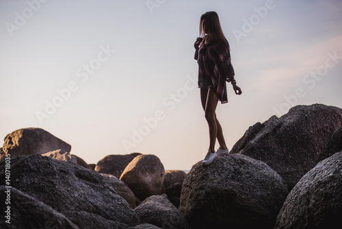 Outdoor summer stylish portrait of beautiful elegant woman with perfect fit body and long legs walking along on the beach,wear summer outfit, posing at sunny day on the beach of sand photo