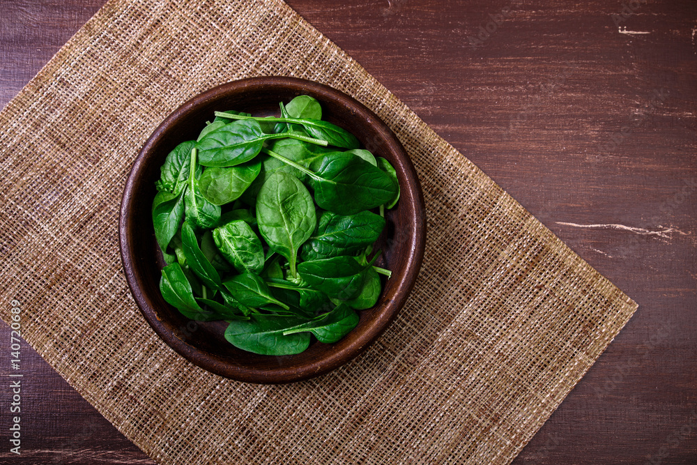 Spinach leaves in bowl. Raw fresh vegetable. Fresh natural plant leaf. Organic bio food on rustic wooden table. Spinach leaves in bowl. Raw fresh vegetable. Fresh natural plant leaf. Organic bio food on rustic wooden table.