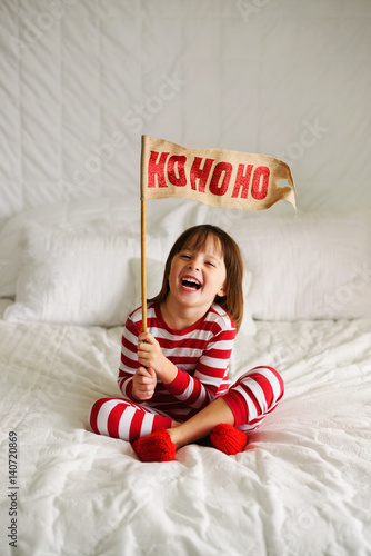 Girl sitting on bed holding a HoHoHo flag photo