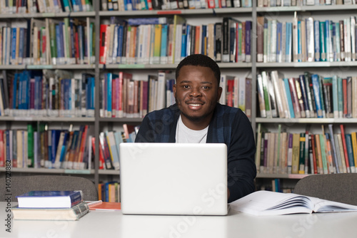 Happy African Male Student With Laptop In Library
