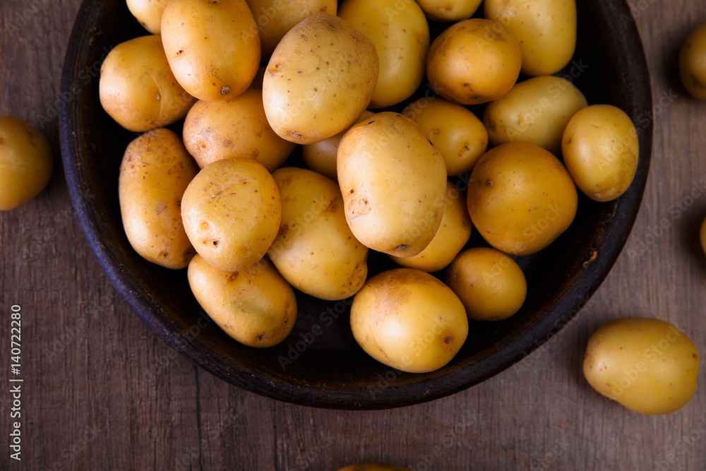 Potatoes in a rustic plate. Raw new potato. Fresh natural vegetables. Organic bio food on wooden table. Potatoes in a rustic plate. Raw new potato. Fresh natural vegetables. Organic bio food on wooden table.