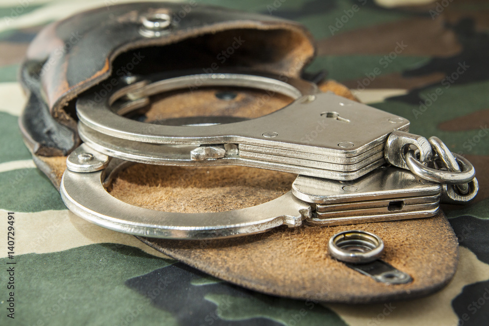 Obraz premium handcuffs on camouflage fabric background