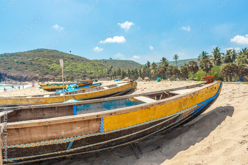 Obraz premium Wide view of group of fishing boats parked alone in seashore with people in the background, Visakhapatnam, Andhra Pradesh, March 05 2017