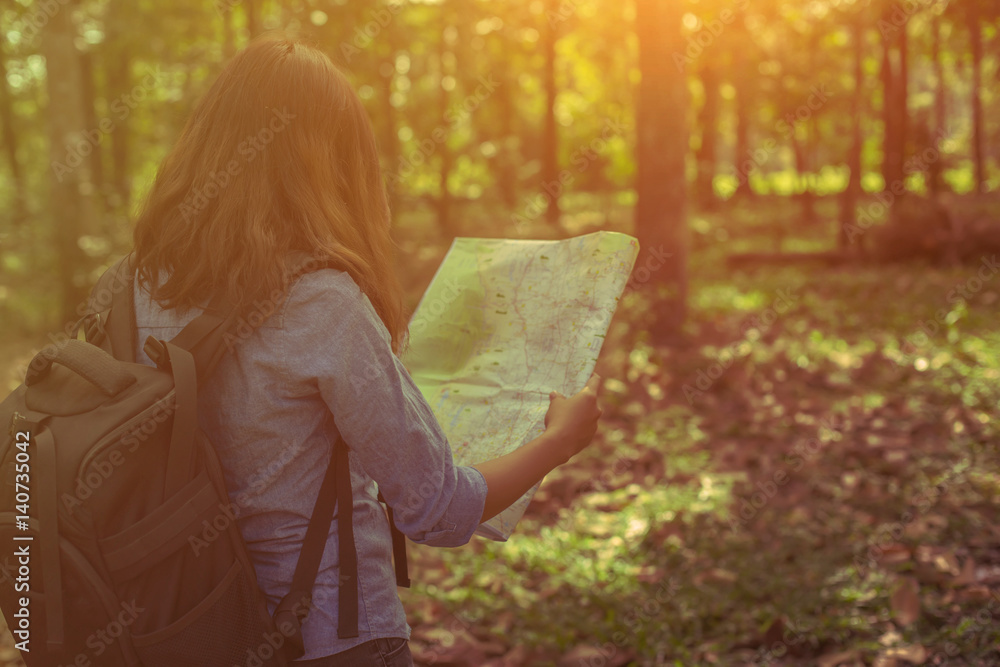 Obraz premium stylish hipster traveler exploring map at sunny forest and lake in the mountains