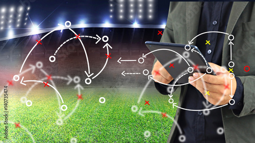 Football manager planning tactic with soccer field and bright spotlights.