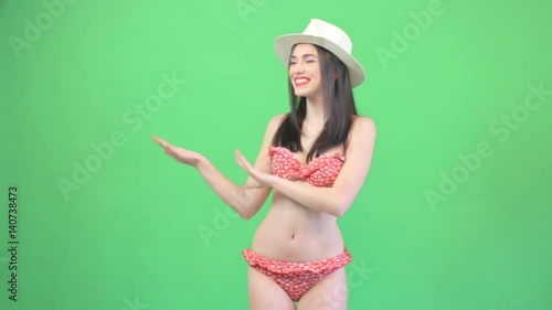 Hawaiian hula girl dancing against a green screen. Perfect slim body, summer style, attractive brunette woman in fashionable colorful bikini