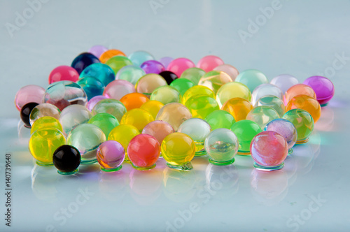 Orbeez balls lay on glass surface on white background. Front view photo