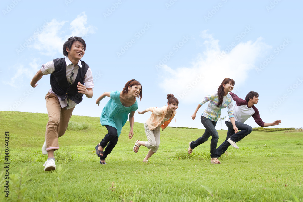 Group of young people running in field Group of young people running in field