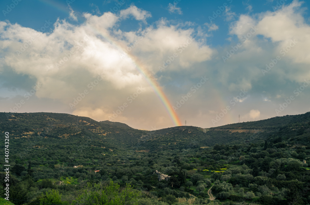 beautiful rainbow over the cretan cloudy mountains. Olive trees in foreground. Typical cretan scenery. 