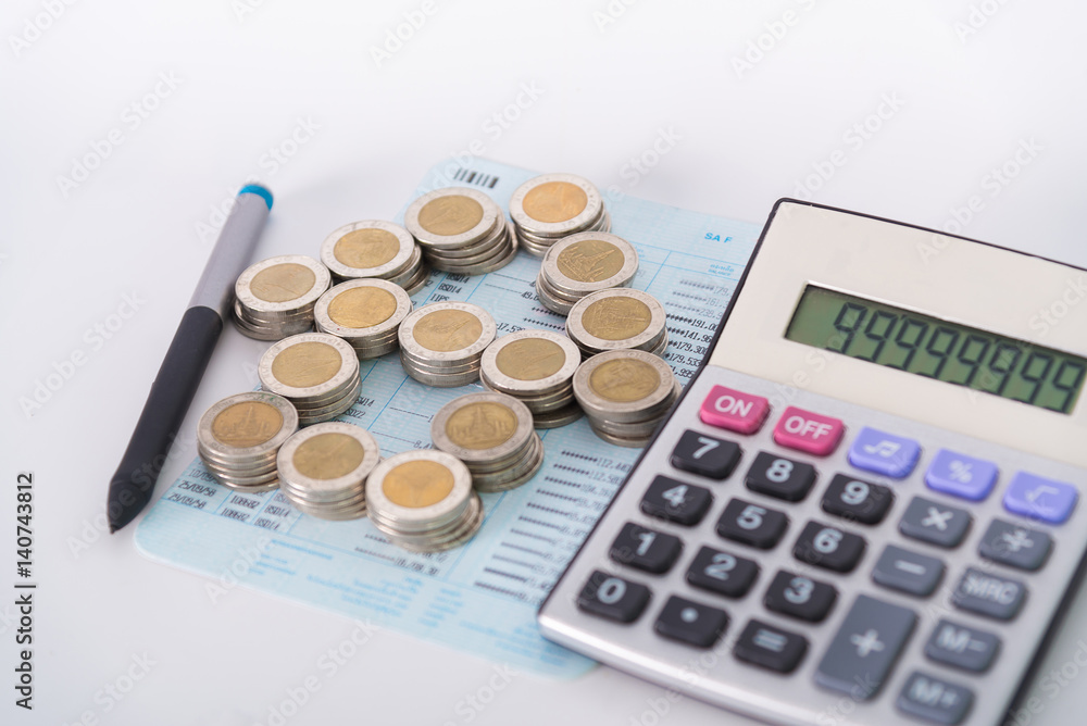 Stack of coins as house shape and calculator on the account book on white background. Stack of coins as house shape and calculator on the account book on white background.