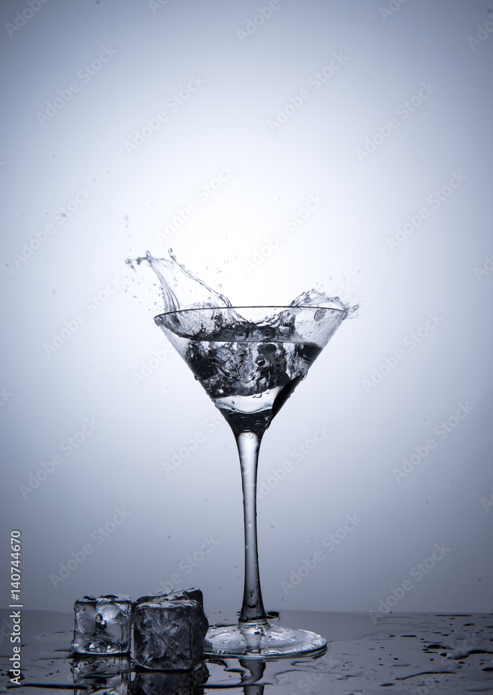 Splash from ice cube in martini glass isolated Splash from ice cube in martini glass isolated