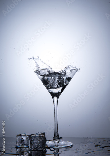 Splash from ice cube in martini glass isolated