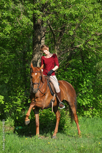 Young horseback rider having pleasure in forest 