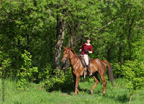 Young woman on a horse ride in forest 