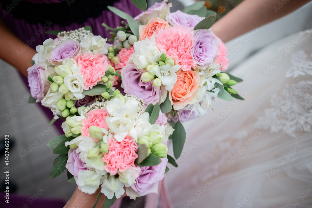 Bride and bridesmaids hold in their hands pink wedding bouquets made of roses and peonies Bride and bridesmaids hold in their hands pink wedding bouquets made of roses and peonies