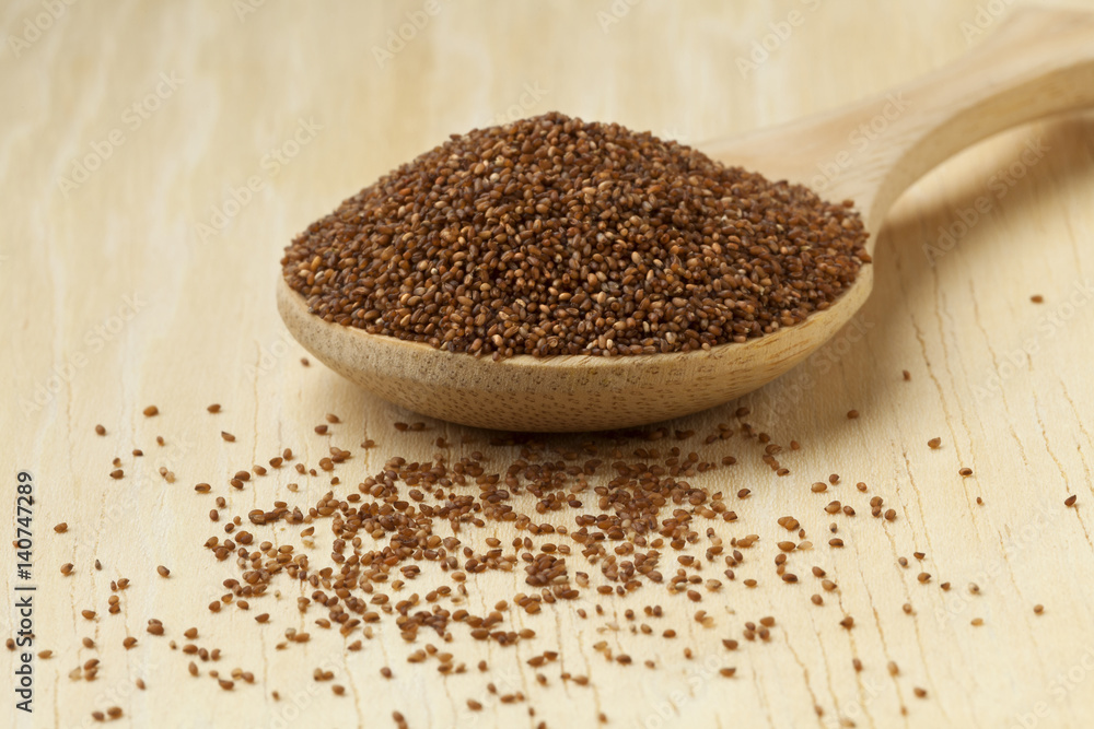 Brown teff seeds on a wooden spoon Brown teff seeds on a wooden spoon