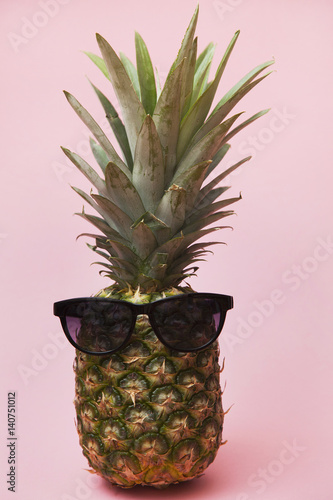 big pineapple on a pink background with sunglasses