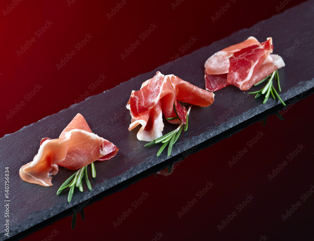 prosciutto with rosemary on a black background