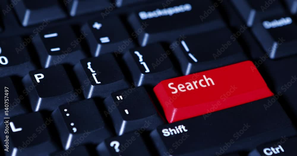Human finger pushes a Search button with red color on the computer keyboard Human finger pushes a Search button with red color on the computer keyboard