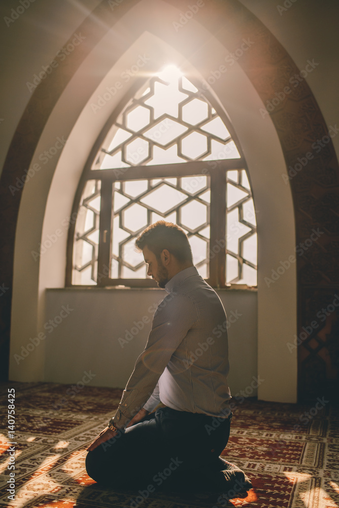Muslim praying next to a window humbly