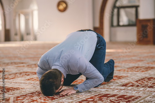 Muslim prostrating on the carpet floor photo