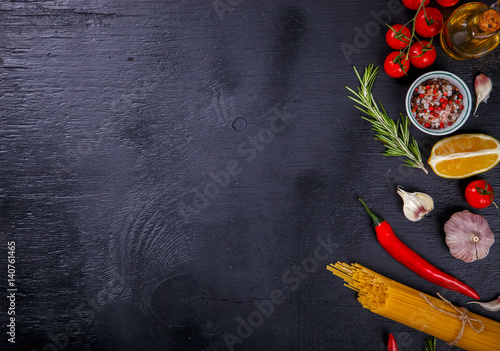 Pasta Spaghetti with Ingredients for cooking pasta on a on Black Background, top view. Copy space for Text. selective focus.