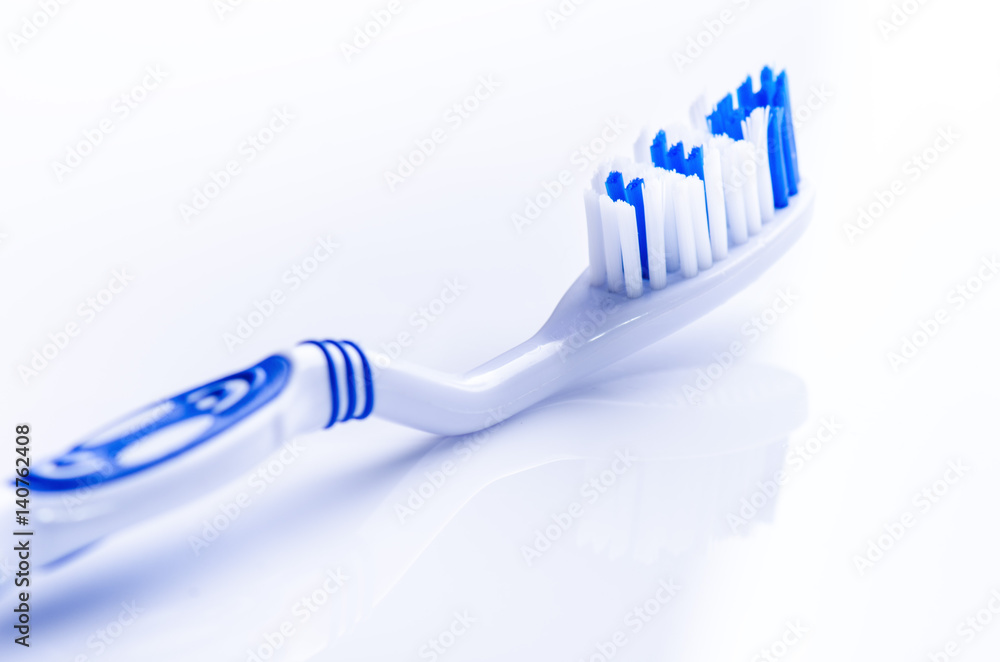 Toothbrush isolated on a white background with reflection. Blue plastic toothbrush. Concept of dental medicine. Toothbrush isolated on a white background with reflection. Blue plastic toothbrush. Concept of dental medicine.
