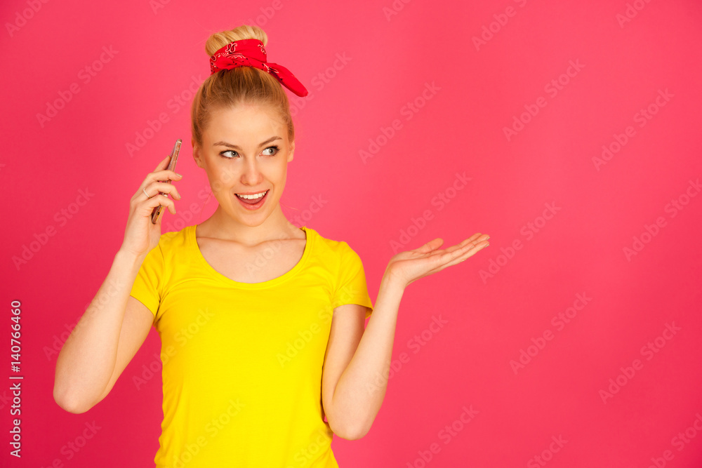cut teenage woman in yellow t shirt talks on smart phone over pink bacckground cut teenage woman in yellow t shirt talks on smart phone over pink bacckground