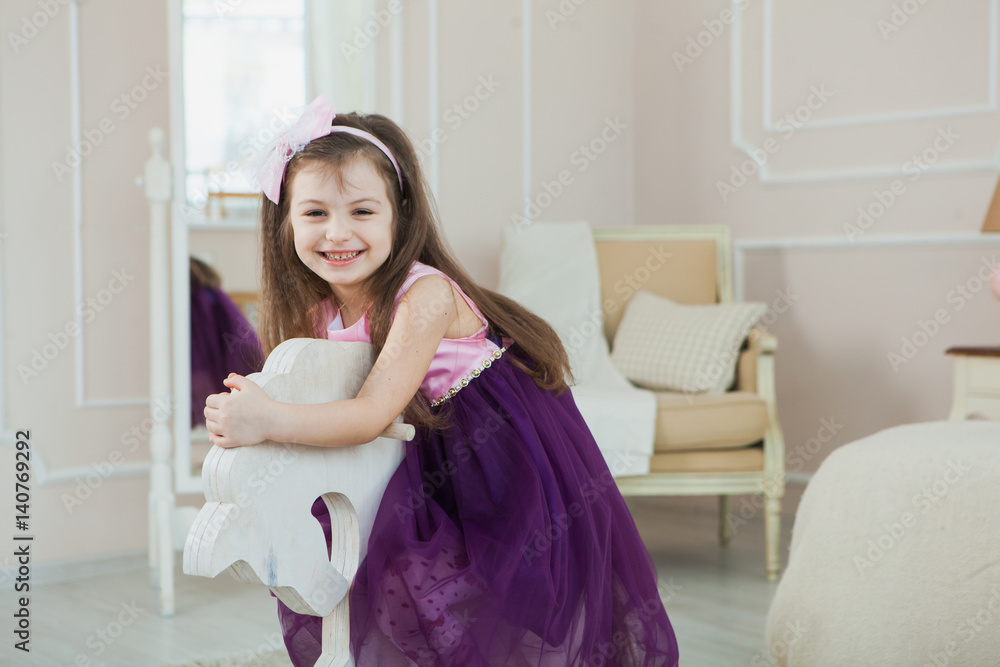 Adorable girl in her room riding her toy horse. Happy child Adorable girl in her room riding her toy horse. Happy child