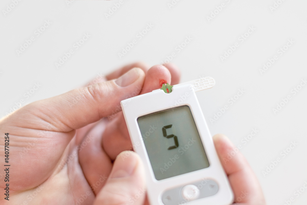 Medicine, diabetes, glycemia, health care and people concept - Close up of man hands testing high blood sugar level with glucometer or glucose meter and test stripe at home Medicine, diabetes, glycemia, health care and people concept - Close up of man hands testing high blood sugar level with glucometer or glucose meter and test stripe at home