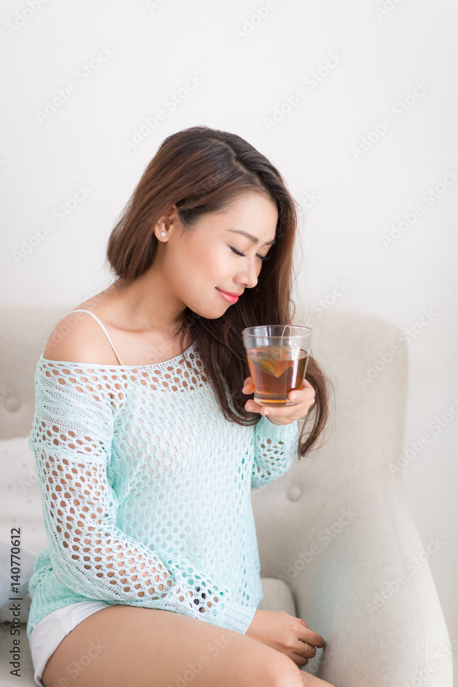 Beautiful young asian woman drinking her morning tea over a breakfast at home. Beautiful young asian woman drinking her morning tea over a breakfast at home.