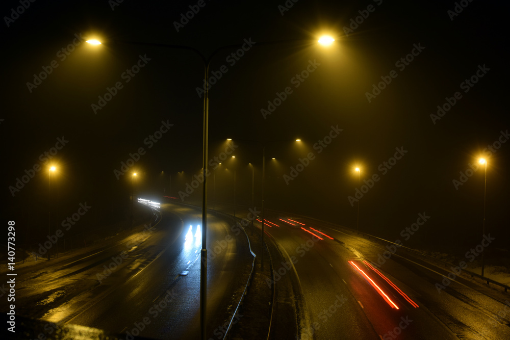 Cars on foggy highway at night.
