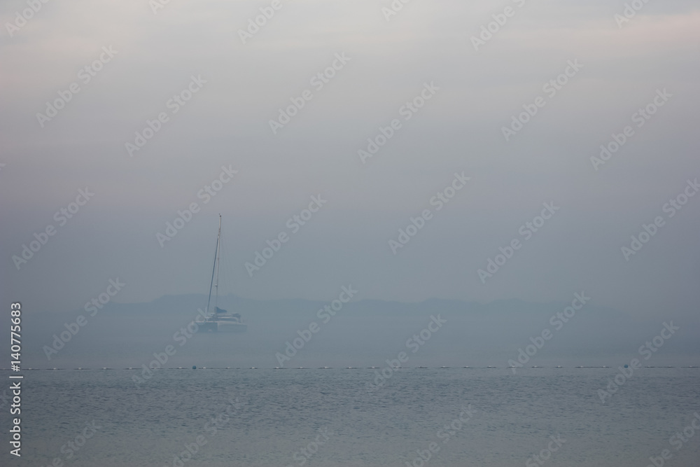Blurred sailboat in the fog-covered sea. 