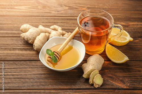 Hot drink with honey, lemon and ginger for cough remedy on wooden table photo