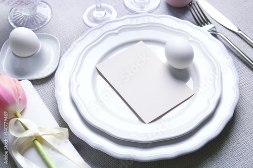 Beautiful Easter table setting with empty card on tablecloth