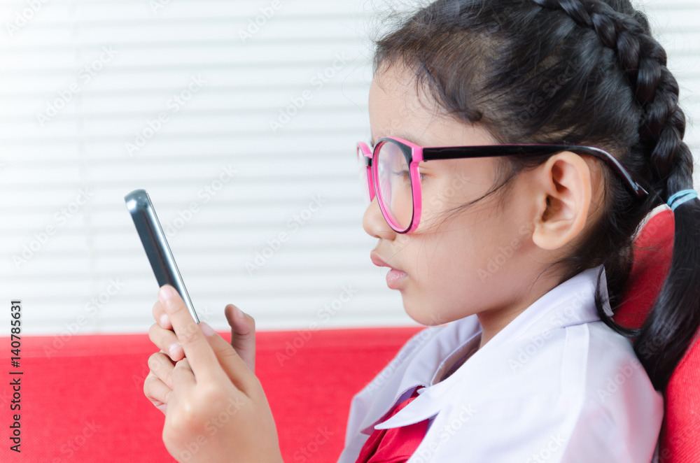 Close up shot Asian little girl in student uniform using smartphone Close up shot Asian little girl in student uniform using smartphone