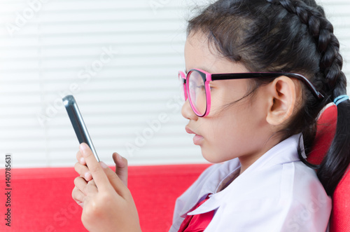 Close up shot Asian little girl in student uniform using smartphone