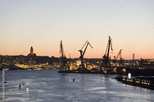 Silhouette cranes at commercial dock by Gota Canal against clear sky during sunset photo