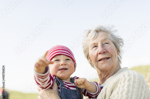 Baby girl with grandmother looking away against clear sky